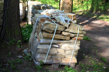 Ormanda depolanmış doğal taş yığınları. İnşaat, peyzaj ve mimari projeler için hazırlanmış yapı malzemeleri.