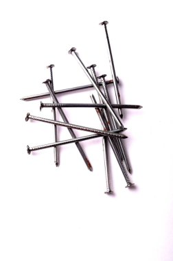 Beyaz arka planda büyük bir demir çivi yığını var.