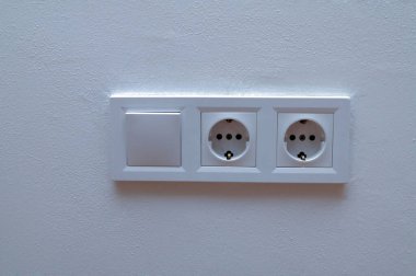 Modern beyaz duvar paneli çift Avrupa elektrik prizi ve lamba anahtarına sahip. Minimalist iç mekan, ev elektriği, ev altyapısı konsepti.