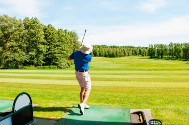 Profesyonel golf sahasında golf oyuncusu. Golf sopasıyla vuruşan golfçü.
