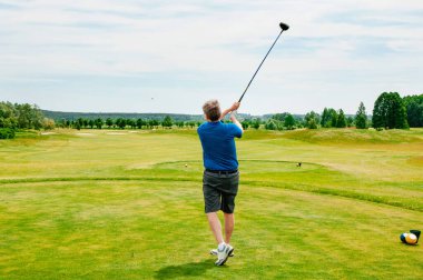 Profesyonel golf sahasında golf oyuncusu. Golf sopasıyla vuruşan golfçü.