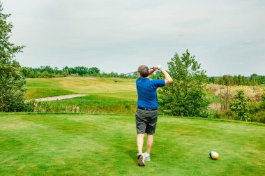 Profesyonel golf sahasında golf oyuncusu. Golf sopasıyla vuruşan golfçü.