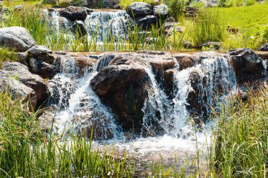 Decorative waterfall with thresholds of large stones in the park clipart