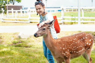 Ukrayna, Mezhygirya, Mayıs 2019. Yaz parkında bir kız, genç bir bambi 'nin kafasını okşadı.