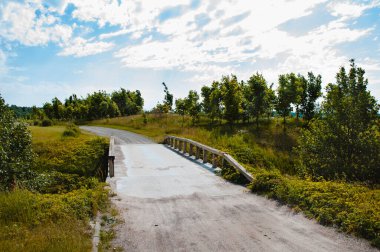 Golf sahasında tahta parmaklıkları olan bir köprü. Güzel doğa ve bulutlu gökyüzü.