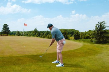 Profesyonel golf sahasında erkek golfçü. Golf sopasıyla vuruşan golfçü.