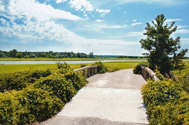 Golf sahasında tahta parmaklıkları olan bir köprü. Güzel doğa ve bulutlu gökyüzü.