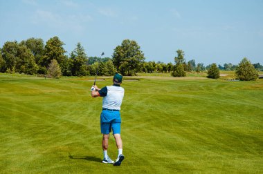 Profesyonel golf sahasında erkek golfçü. Golf sopasıyla vuruşan golfçü.