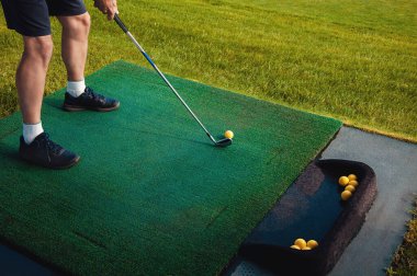 Profesyonel golfçü topu deliğe sokuyor. Güneşli bir günde arka planda oyuncuyla deliğin kenarında golf topu.