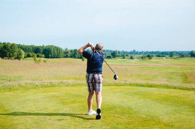 Bir sporcu golf oynar ve golf sahasında topa vurur..