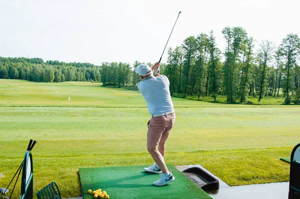 A sports man plays golf and kicks the ball on the golf course.