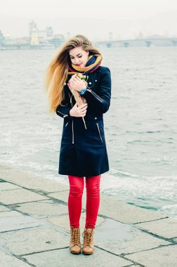 Kış gezintisinde elinde bir buket gülle güzel, genç, neşeli bir sarışın. Sevgililer Günü