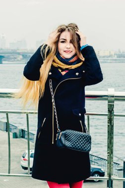 Genç güzel sarışın köprüde duruyor ve gülümsüyor. Kış portresi.