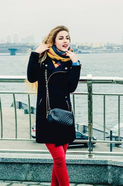 Genç güzel sarışın köprüde duruyor ve gülümsüyor. Kış portresi.