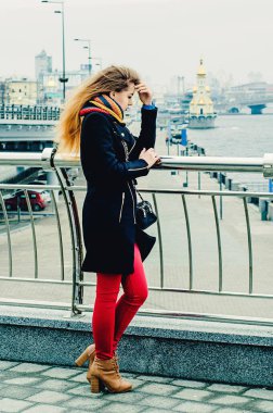 Genç, güzel sarışın köprüde duruyor ve üzgün. Kış portresi.