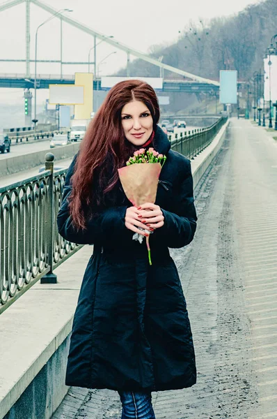 橋の上にバラの花束を持つ美しい若い赤髪の女の子笑顔 — ストック写真