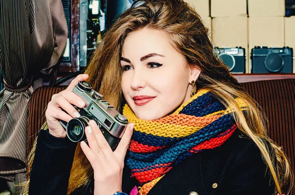 ヴィンテージカメラを持つ若い美しいブロンドの女性がカフェで写真を撮ります 写真家の冬の肖像 — ストック写真