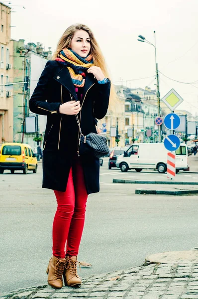 冬服の若い美しいブロンドは 街の背景と笑顔を背景に歩道に立っています — ストック写真