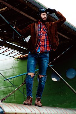 Sakallı genç pilot, eski bir uçağın kanadında dikiliyor..