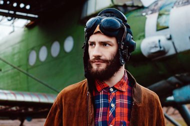 Cebinde bir haritayla gezgin pilot klasik bir uçağın arka planında duruyor..