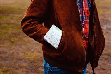 Cebinde harita olan bir gezgin klasik bir uçağın arka planında duruyor..