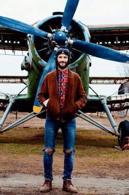 Cebinde bir haritayla gezgin pilot klasik bir uçağın arka planında duruyor..