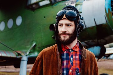 Cebinde bir haritayla gezgin pilot klasik bir uçağın arka planında duruyor..