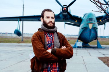 Cebinde bir haritayla gezgin pilot klasik bir uçağın arka planında duruyor..