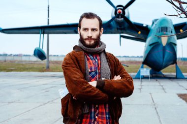 Cebinde bir haritayla gezgin pilot klasik bir uçağın arka planında duruyor..