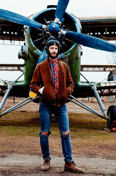 彼のポケットに地図を持つ男のパイロット旅行者は ヴィンテージ飛行機を背景に立っている — ストック写真