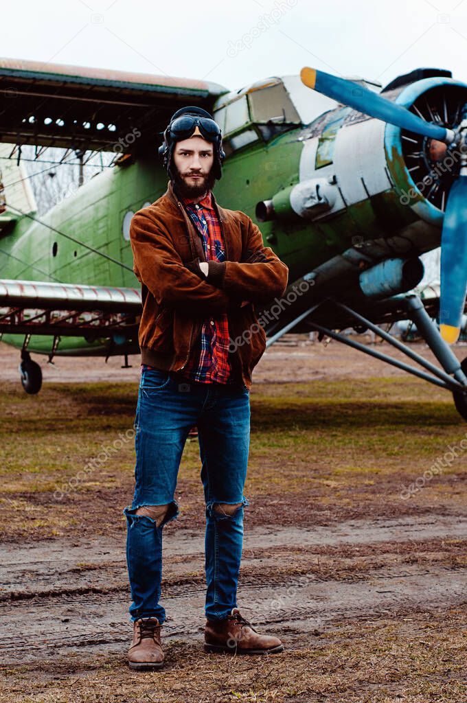 Bearded young pilot on the background of a vintage aircraft.