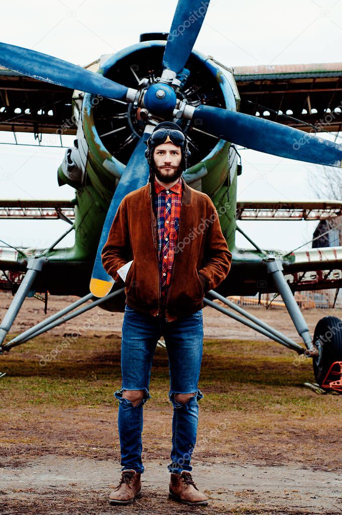 Man pilot traveler with a map in his pocket stands against the backdrop of a vintage airplane.