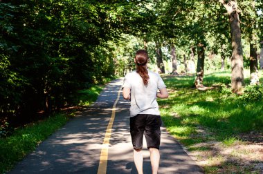 Genç adam yolda koşuyor - gün batımını aydınlatıyor