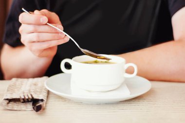 Restoranda bir adam tavuk çorbası içiyor.