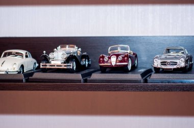 Dolaptaki kürsüde dört antika eski arabanın modelleri..