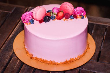 Bisküvi, reçel, ahududu, çilek, yabanmersini ve ahududu gülleriyle süslenmiş şenlikli pembe bir pasta..