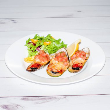 Yakın plan görüntü ızgara midye, salata ve limonlu peynir.