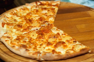 Sıcak pizza dilimi, erimiş peynirle ahşap bir masada..