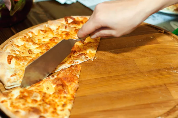 Hot pizza slice with melting cheese on a rustic wooden table.