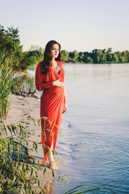 Kiev Denizi akşamında, uzun kırmızı elbiseli güzel hamile esmer, Temmuz 2015