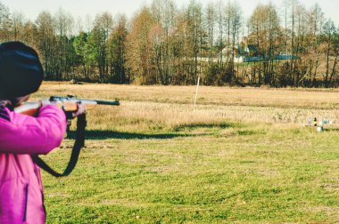 Bir kız tarlada ateş ediyor.