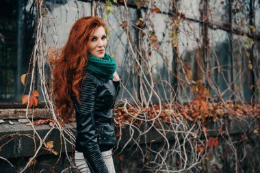 Uzun kızıl saçlı bahar güzeli kız dışarıda saç üflüyor. Çiçek açan ağaçlar. Romantik genç kadın portresi. Doğa