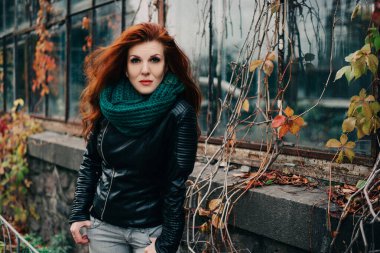 Uzun kızıl saçlı bahar güzeli kız dışarıda saç üflüyor. Çiçek açan ağaçlar. Romantik genç kadın portresi. Doğa