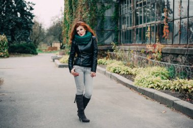 Uzun kızıl saçlı bahar güzeli kız dışarıda saç üflüyor. Çiçek açan ağaçlar. Romantik genç kadın portresi. Doğa