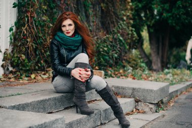 Uzun kızıl saçlı bahar güzeli kız dışarıda saç üflüyor. Çiçek açan ağaçlar. Romantik genç kadın portresi. Doğa