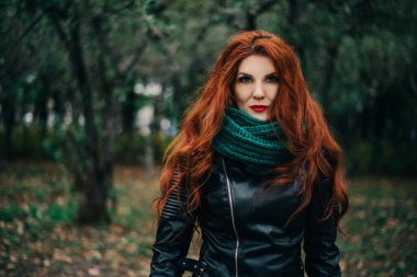 Uzun kızıl saçlı bahar güzeli kız dışarıda saç üflüyor. Çiçek açan ağaçlar. Romantik genç kadın portresi. Doğa