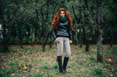 Uzun kızıl saçlı bahar güzeli kız dışarıda saç üflüyor. Çiçek açan ağaçlar. Romantik genç kadın portresi. Doğa