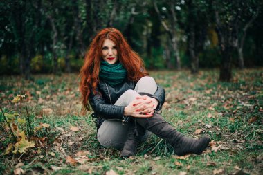 Uzun kızıl saçlı bahar güzeli kız dışarıda saç üflüyor. Çiçek açan ağaçlar. Romantik genç kadın portresi. Doğa