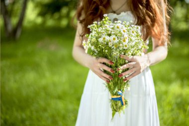 Uzun kızıl saçlı bahar güzeli kız dışarıda saç üflüyor. Çiçek açan ağaçlar. Romantik genç kadın portresi. Doğa