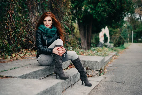 Uzun kızıl saçlı bahar güzeli kız dışarıda saç üflüyor. Çiçek açan ağaçlar. Romantik genç kadın portresi. Doğa